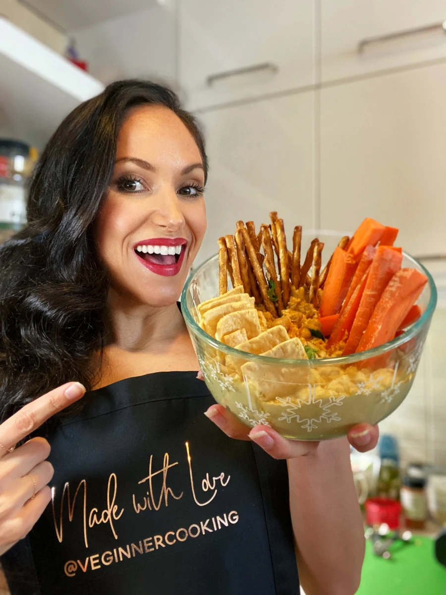Cheryl presenting a bowl of dip with vegetables, crackers, and pretzels