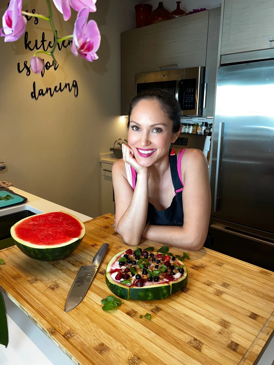 Cheryl in her kitchen with a colorful fruit-topped watermelon